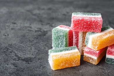 Pile of fruit jelly candies on grey table, closeup. Space for text