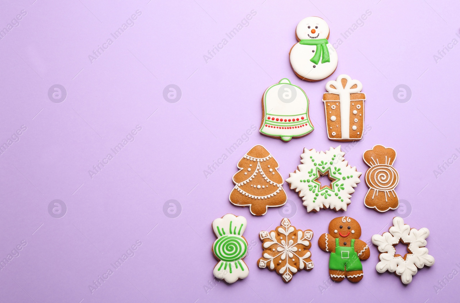 Photo of Christmas tree shape made of delicious gingerbread cookies on lilac background, flat lay. Space for text