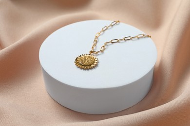 Photo of Stylish presentation of elegant necklace on beige cloth, closeup