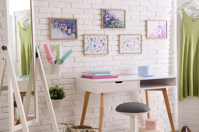 Photo of Stylish room interior with different artworks and table
