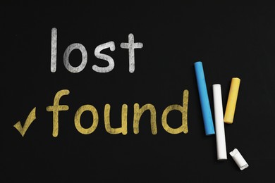 Phrase Lost and Found written colorful chalks on blackboard, flat lay