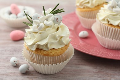 Tasty Easter cupcakes with vanilla cream on wooden table, closeup