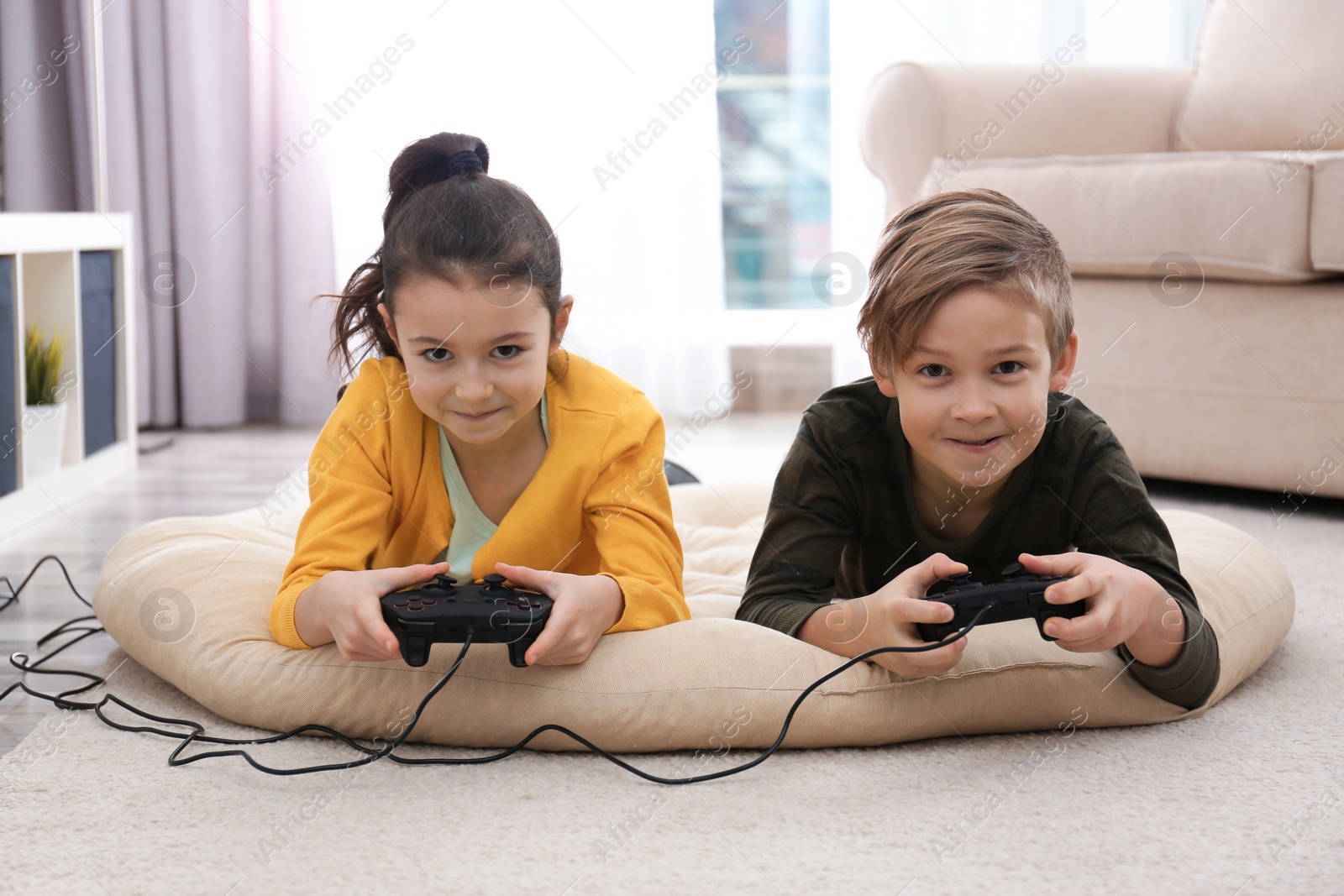 Photo of Cute children playing video games on floor at home