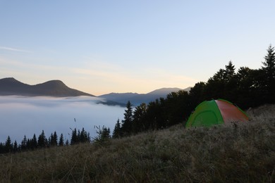Photo of Picturesque mountain landscape with camping tent in foggy morning. Space for text