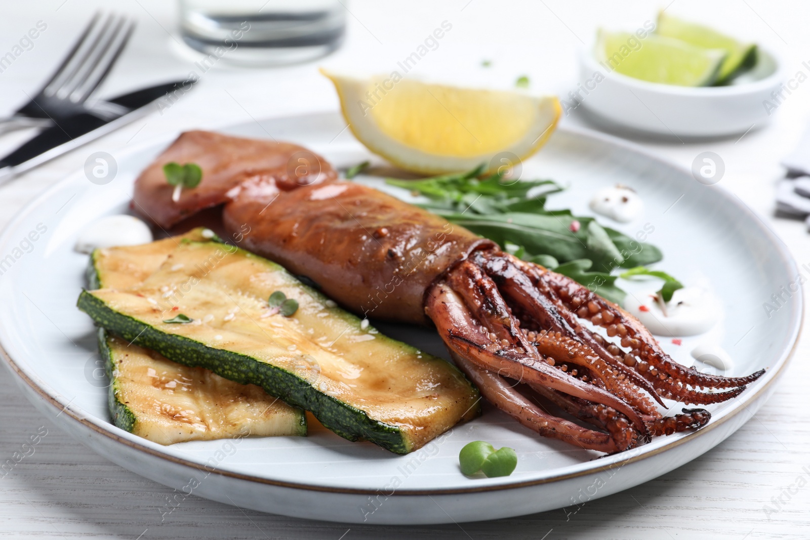 Photo of Delicious grilled squid served on white wooden table, closeup