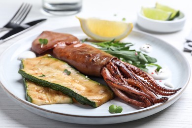 Photo of Delicious grilled squid served on white wooden table, closeup