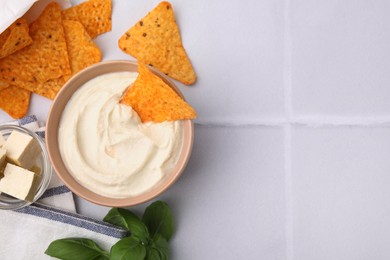 Photo of Delicious tofu sauce served with nachos chips on white tiled table, flat lay. Space for text