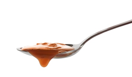 Photo of Spoon of tasty caramel sauce isolated on white