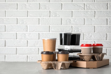 Various takeout containers on table against white brick wall, space for text. Food delivery service