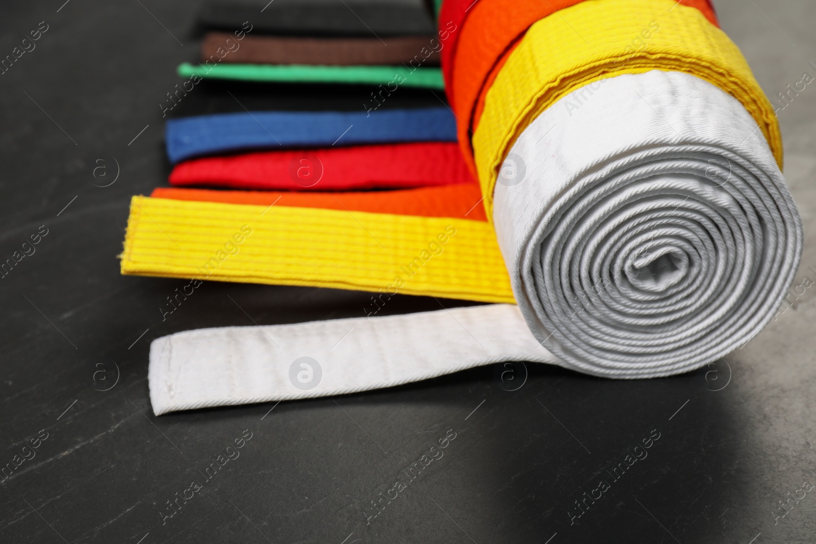Photo of Colorful karate belts on gray background, closeup