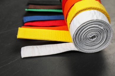 Photo of Colorful karate belts on gray background, closeup