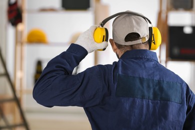 Photo of Worker wearing safety headphones indoors, back view. Hearing protection device