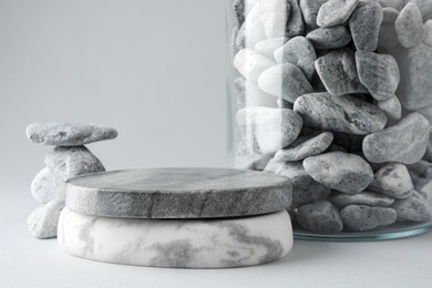 Photo of Presentation for product. Podium and glass container with stones on light grey background. Space for text