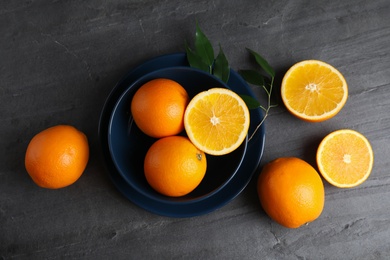 Photo of Fresh oranges and bowl on grey table, top view