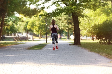 Young woman running in park on sunny day