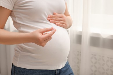 Photo of Pregnant woman with pill at home, closeup