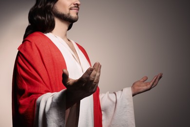 Photo of Jesus Christ reaching out his hands on beige background, closeup