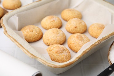 Photo of Tasty sweet sugar cookies in baking dish on white tiled table, closeup