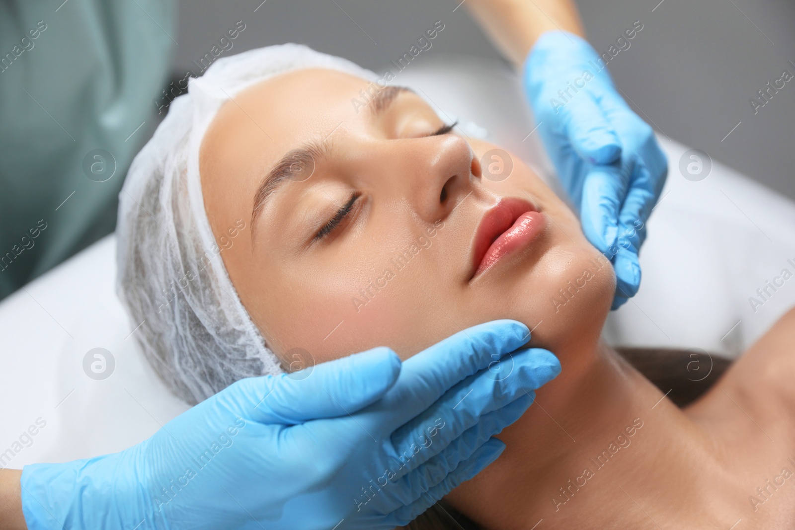 Photo of Young woman receiving facial massage in salon