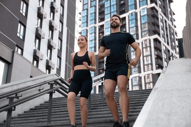 Healthy lifestyle. Happy couple running on steps outdoors, low angle view