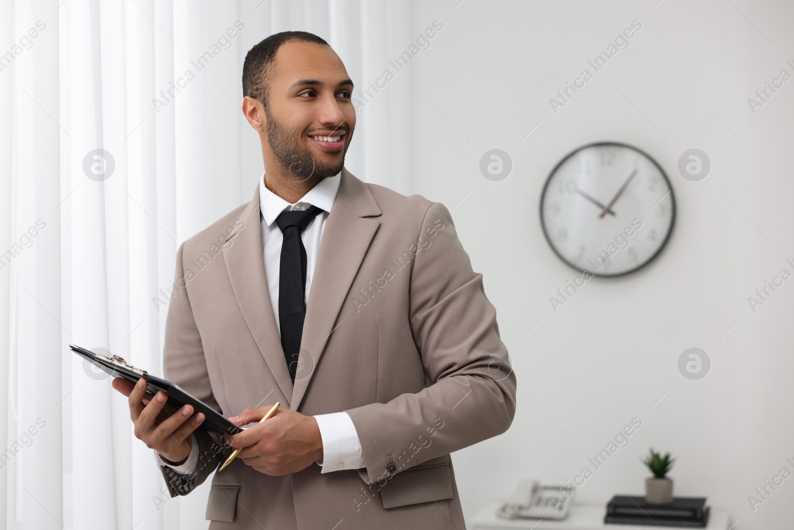 Photo of Portrait of smiling young man with clipboard and pen in office, space for text. Lawyer, businessman, accountant or manager