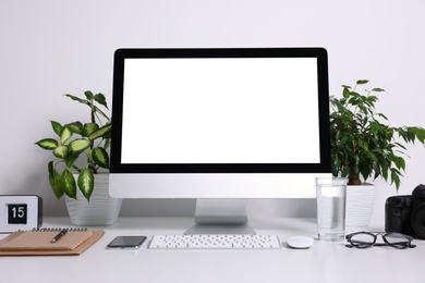 Comfortable workplace with modern computer on table near white wall. Space for text