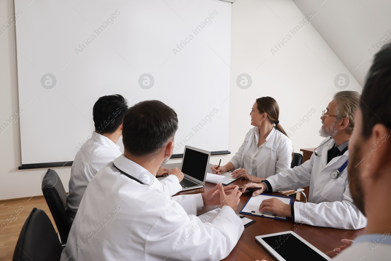 Photo of Team of doctors using video projector during conference indoors