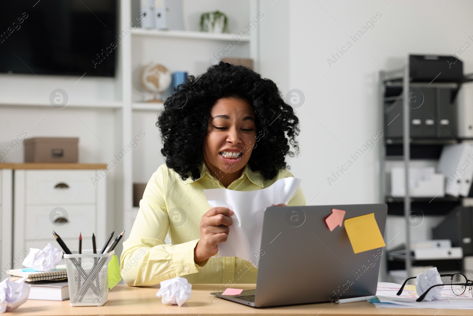 Photo of Deadline concept. Stressed woman crumpling document at wooden table in office