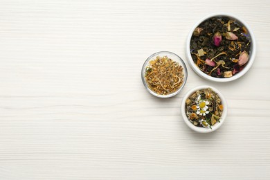 Flat lay composition with different dry teas on white wooden table, space for text