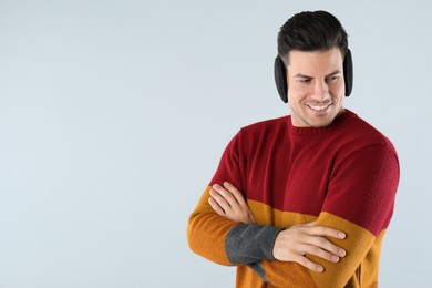 Photo of Man wearing stylish earmuffs on light background. Space for text