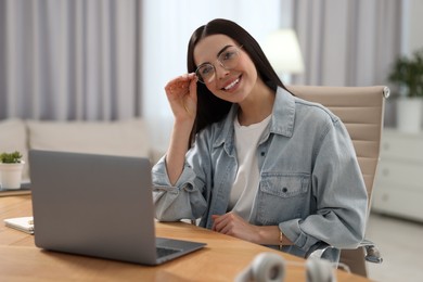 Photo of Young woman watching webinar at table in room