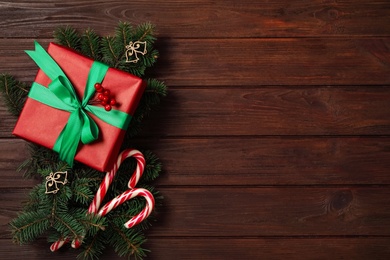 Photo of Christmas composition with gift box and festive decor on wooden table, flat lay. Space for text