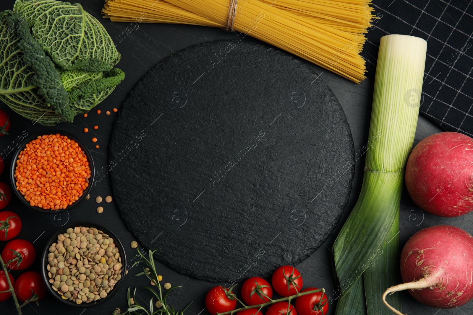 Photo of Slate plate surrounded by different ingredients on black table, flat lay with space for text. Cooking classes