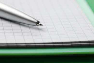Photo of Ballpoint pen and paper sheets on green background, closeup