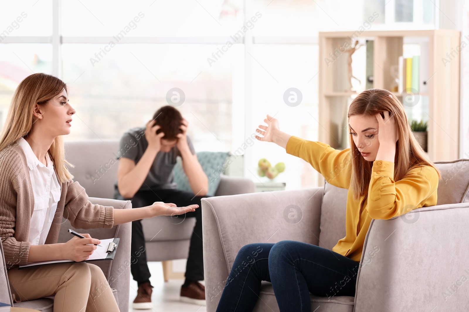 Photo of Young female psychologist working with teenage boy and his mother in office