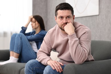 Offended couple ignoring each other after quarrel indoors, selective focus. Relationship problems