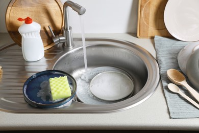 Washing plates and sponge in kitchen sink