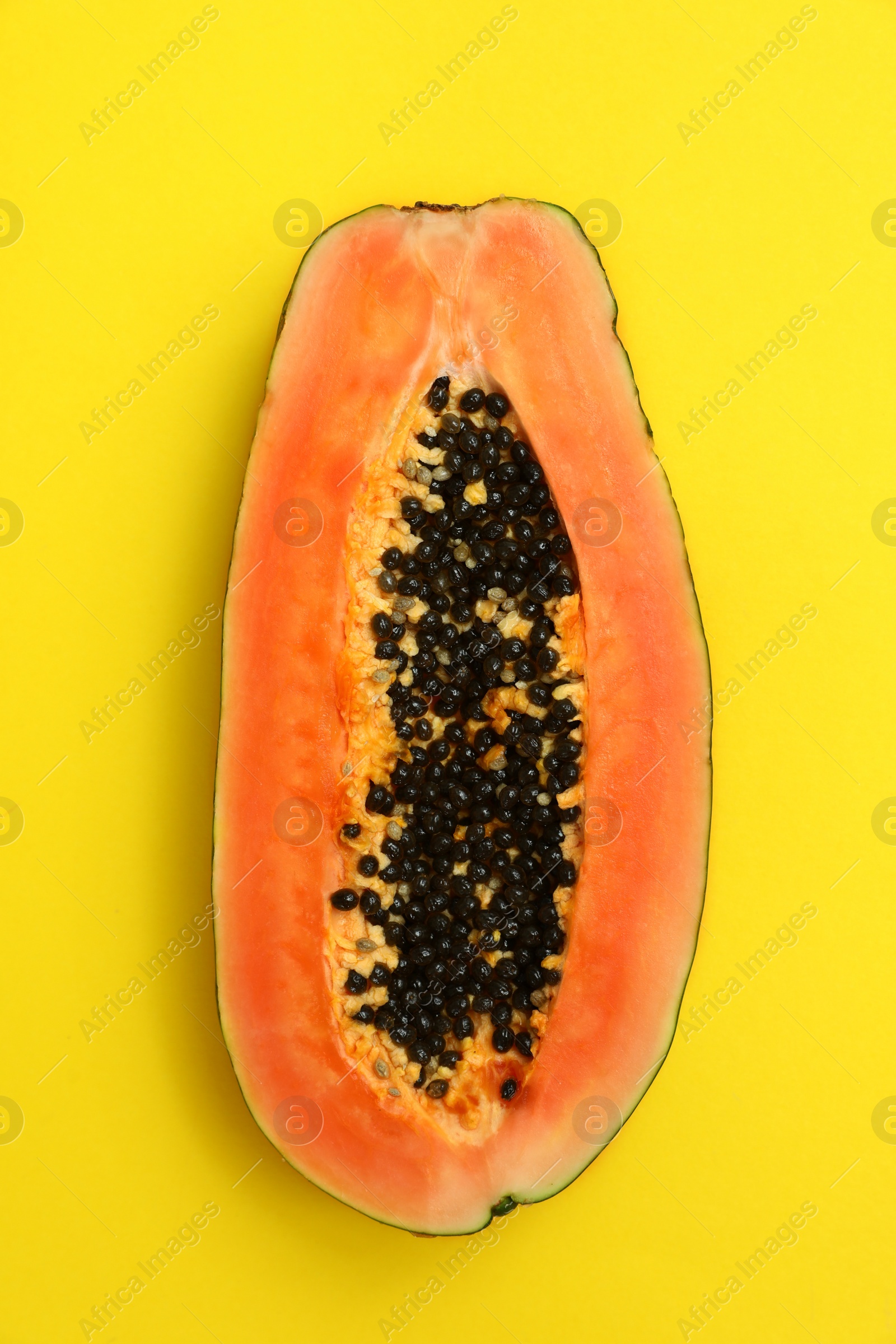 Photo of Fresh juicy halved papaya on yellow background, top view