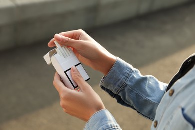 Photo of Woman taking cigarette out of pack outdoors, closeup