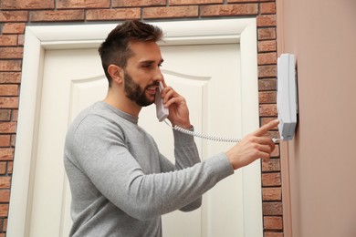 Man with handset answering intercom call indoors