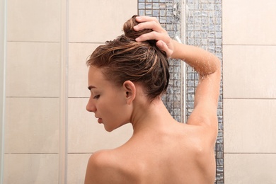 Beautiful young woman taking shower at home