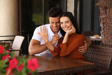 Photo of Lovely couple showing beautiful engagement ring in outdoor cafe