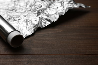 Roll of foil paper on wooden table, space for text