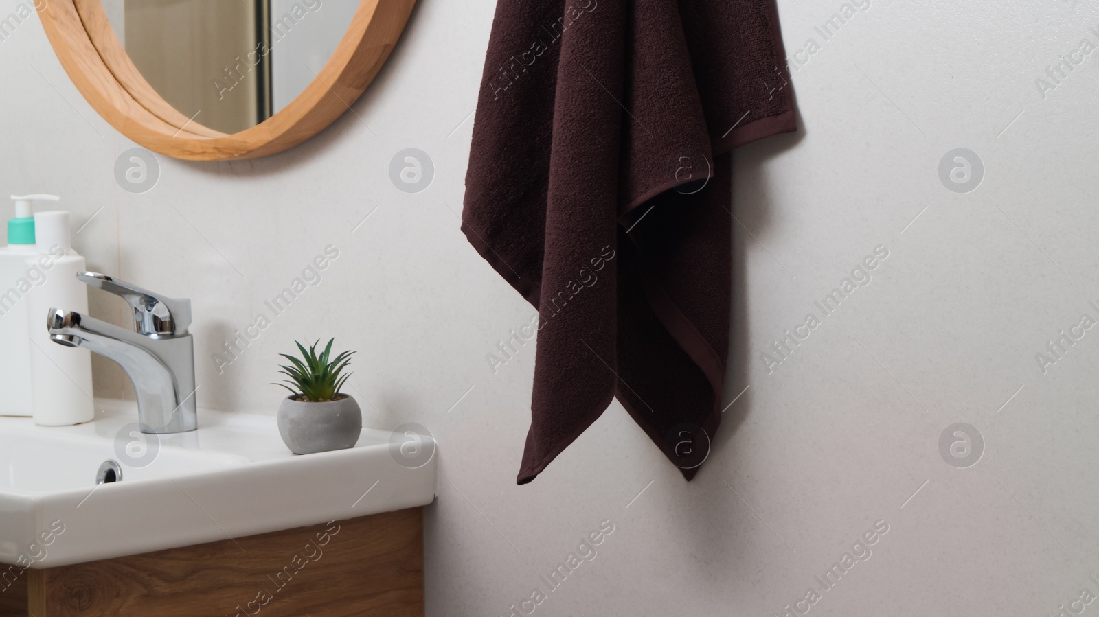 Photo of Brown soft towel hanging on grey wall in bathroom