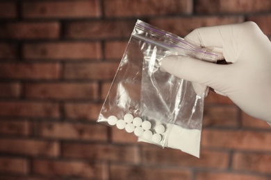Photo of Police worker holding drugs in plastic bags, closeup. Space for text