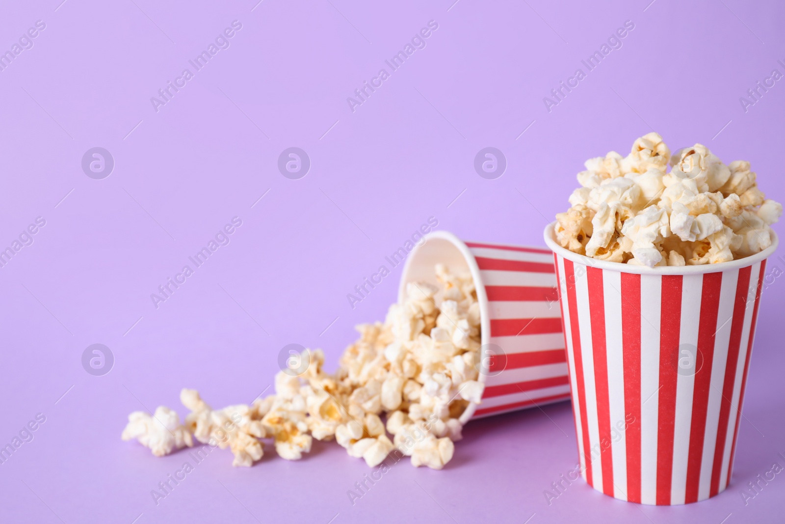 Photo of Delicious popcorn on lilac background. Space for text