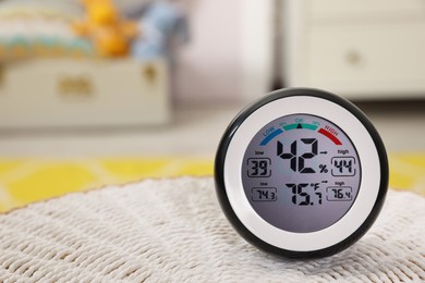 Photo of Digital hygrometer with thermometer on mat in room, closeup. Space for text