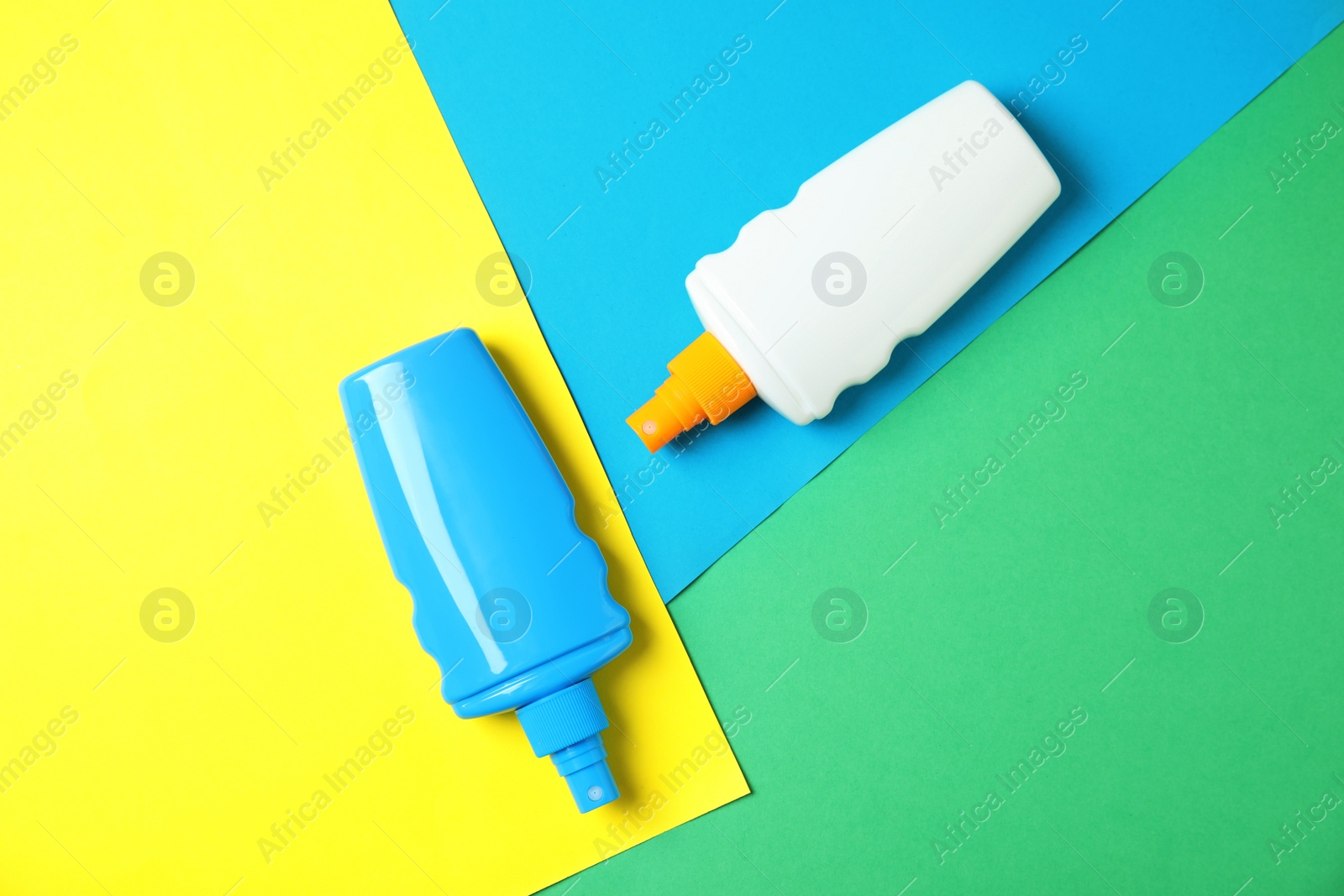 Photo of Bottles with sun protection body cream on color background, top view