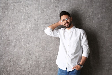 Portrait of handsome smiling man in glasses on grey background. Space for text