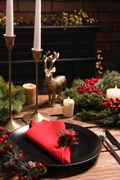 Plate with red fabric napkin, cutlery and festive decor on wooden table